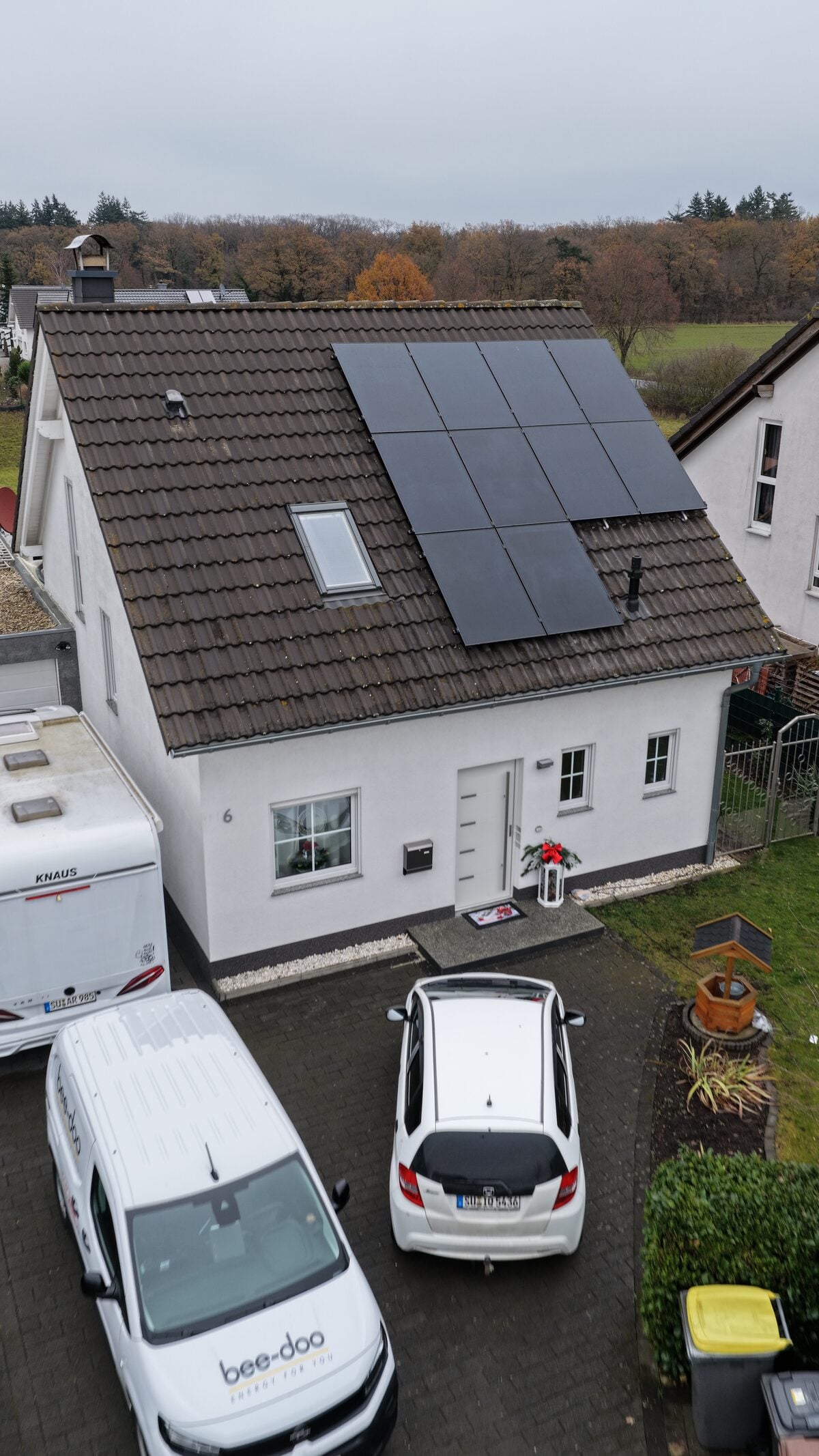 Weißes Einfamilienhaus mit PV-Anlage und bee-doo Transporter